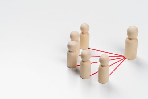 Wooden peg dolls are connected together with red lines on white